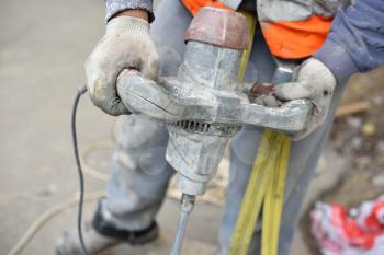 Worker holding a mixer cement tool, hands close up.