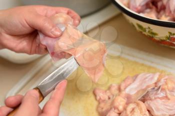 Woman cuts off excess chicken skin. close up.