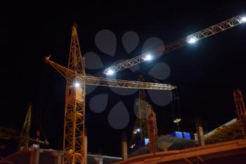 Large construction crane works at night. Night shift construction.