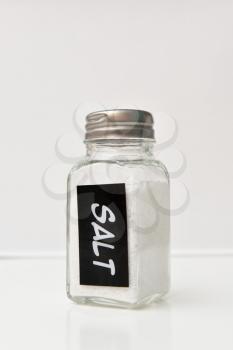 A small jar with salt on a white background, with an inscription.