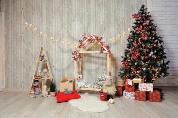 New Year or Christmas photo zone for children. Children's photo zone with a wooden house, toys, a Christmas tree and gifts in a warm light.