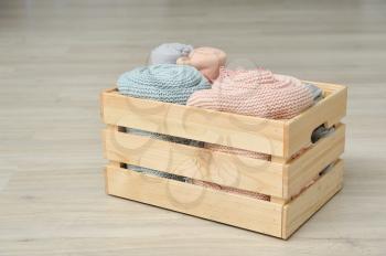 Wooden box with warm knitted plaids of pink and blue color. Close up.