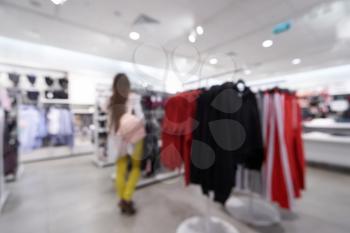 Beautiful blurred background of a women's clothing store in a mall, a girl walks and chooses clothes. Defocused