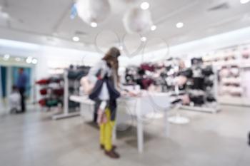 Beautiful blurred background of a women's clothing store in a mall, a girl walks and chooses clothes. Defocused