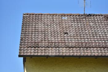 The roof of the house with old tiles on a background of blue sky