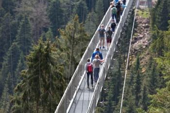 Strong metal ropes hold the suspension bridge, which are tourists in the German forest