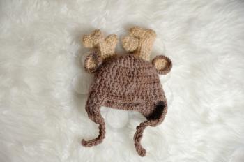 Cute children's knitted hat in the shape of a deer on a white carpet background