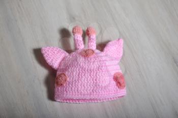 Cute children's knitted hat with ears and horns on a wooden surface background