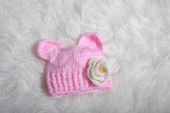 Cute children's knitted hat with ears like a mouse on a white carpet