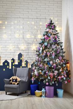 Interior of a children's playroom decorated for the New Year holiday, with a Christmas tree, an armchair and soft toys