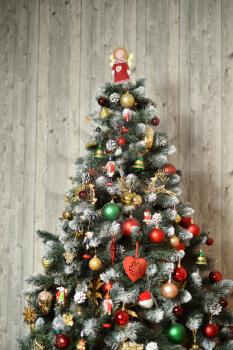 Decorated Christmas tree on a background of a wooden wall. Top of christmas tree