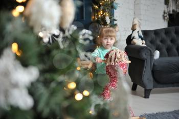 Little girl child sitting on a red rocking horse on a background of Christmas interior