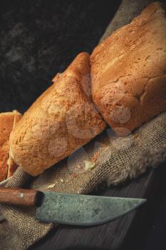 Freshly baked bread lies on a cutting board and on burlap.