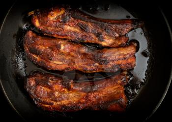 Juicy fried pork ribs in a pan