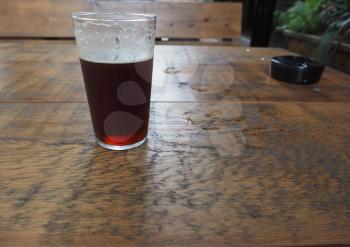 a pint of British ale beer on a wooden pub table