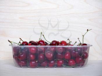 red cherries in a plastic basket on wooden table