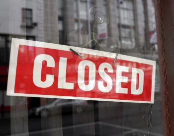 Closed sign in a shop showroom with reflections - red sign over desaturated background