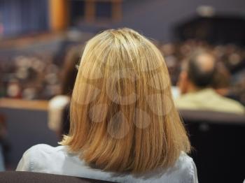 Unrecognisable woman attending an event, seen from behind
