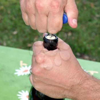 Hand opening a bottle of wine on a table