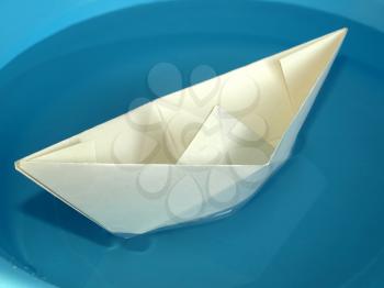 Toy paper boat over a blue water background