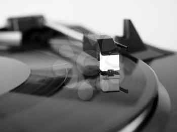 Vinyl record spinning on a turntable, focus on needle - in black and white