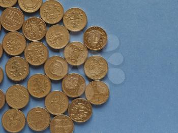 One Pound coins money (GBP), currency of United Kingdom over blue background with copy space