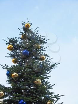 Christmas tree with baubles decorations over blue sky with copy space