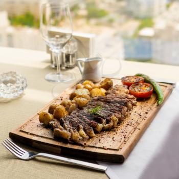 Tasty steak with potato, vegetable on the wood plate