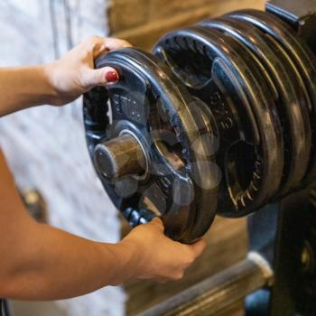 A young woman preparing barbell for working out close up