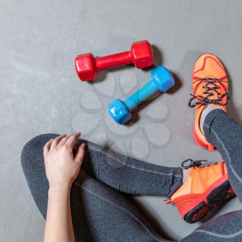 Fitness woman legs with colorful dumbbells top view