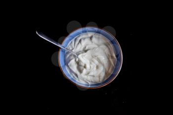 a blue bowl filled with yogurt on a black background