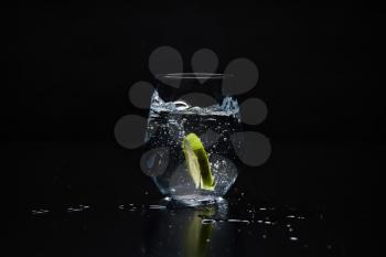 a clear glass with lemonade on a black background