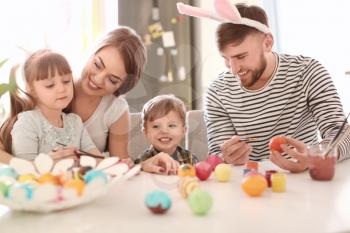 Family painting Easter eggs together at table�