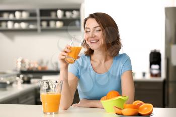 Beautiful woman drinking citrus juice in kitchen�