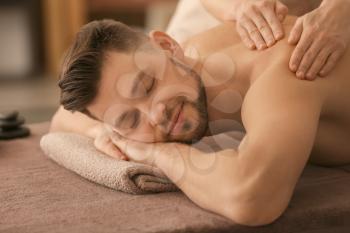 Young man receiving massage at spa salon�