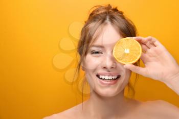 Beautiful young woman with citrus fruit on color background�