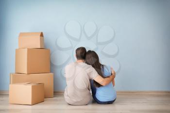 Young couple resting near boxes indoors. Moving into new house�
