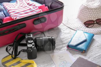 Tourist's stuff with open travel suitcase on wooden background�