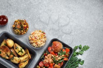 Different containers with delicious food on grey background�