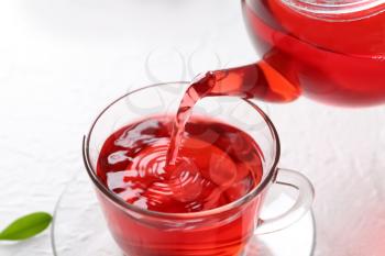 Pouring hot red tea into glass cup on table�