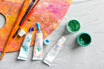 Jars and tubes of paints with brushes and palette on table�