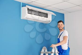 Electrician repairing air conditioner indoors�