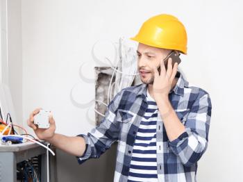 Electrician talking on phone near distribution board indoors�