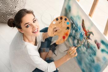 Female artist painting picture in workshop�