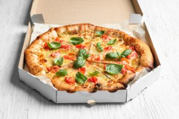 Carton box with delicious pizza Margherita on wooden background�