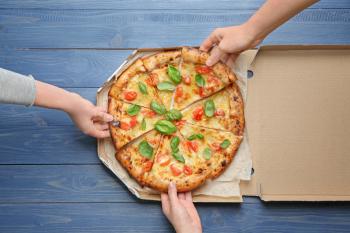 Young people taking slices of delicious pizza Margherita from box�