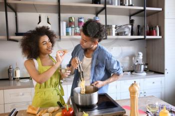 Young African-American couple cooking together in kitchen�