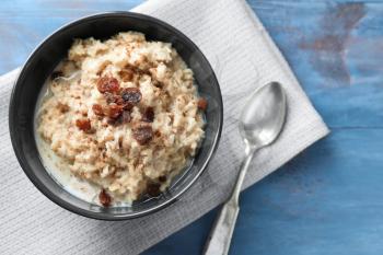 Tasty oatmeal with raisins in bowl on table�