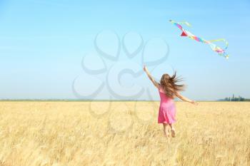 Beautiful young woman flying kite in a field�