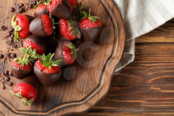 Board with tasty chocolate dipped strawberries on wooden table�